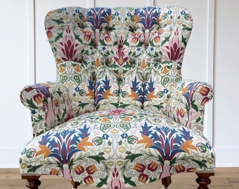 Armchair chair seat in a printed floral leaf William Morrison -style design. Pink red blue green gold cream