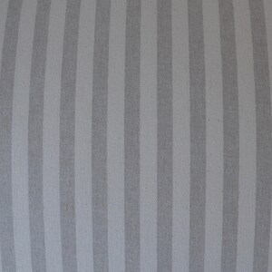 May include: A close-up of a grey and white striped fabric. The fabric has a subtle sheen and a smooth texture.