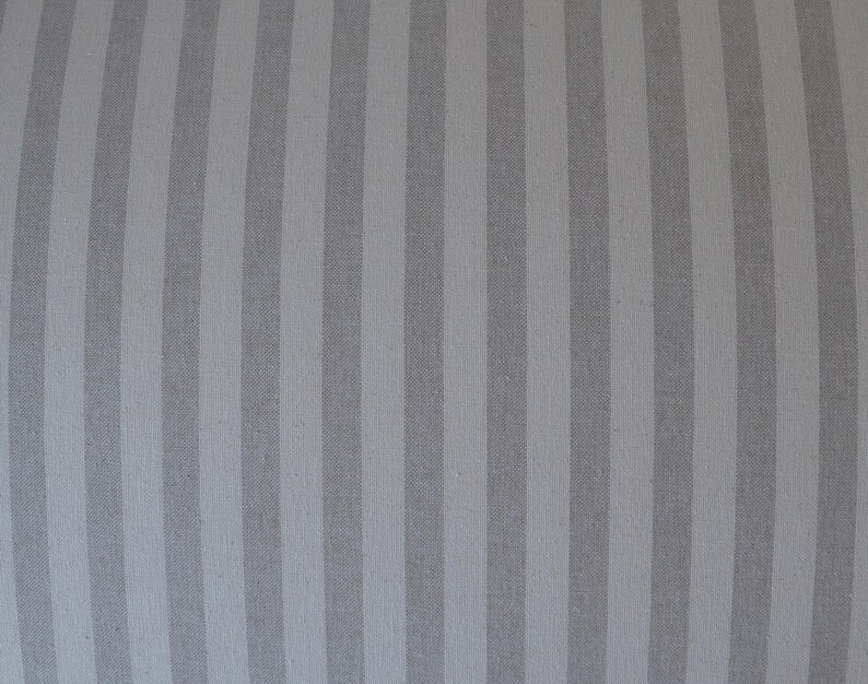 May include: A close-up of a grey and white striped fabric. The fabric has a subtle sheen and a smooth texture.