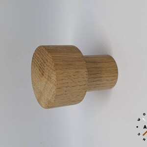 May include: A light brown wooden knob with a rounded top and a cylindrical base. The knob is made of solid wood and has a natural finish.
