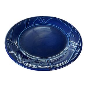 May include: A deep blue ceramic plate with a raised geometric design around the rim.