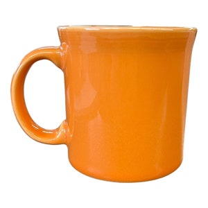 Puede incluir: Una taza de cerámica naranja vibrante con un asa curvada. La taza tiene un acabado brillante y un diseño simple y clásico. Perfecta para café, té o cualquier bebida favorita. Una adición brillante y alegre a cualquier cocina u oficina.