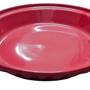 May include: A red ceramic pie dish with a glossy finish. The dish has a slightly raised rim and a scalloped edge. This kitchenware is perfect for baking pies and other desserts.