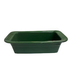 May include: A rectangular, emerald green ceramic loaf pan with a glossy finish. The pan has a slightly flared rim and a series of horizontal ridges along the sides. The interior is smooth and empty.