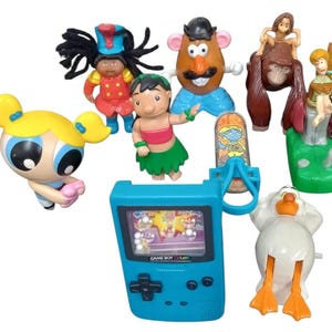 May include: A collection of colorful character figurines, including a blue Game Boy Color, a Mr. Potato Head, and characters from Powerpuff Girls, Lilo & Stitch, and Tarzan. The toys are made of plastic and are in various poses.