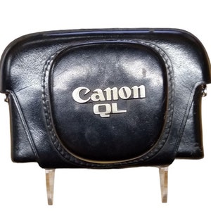 May include: Black leather camera case with a silver Canon QL logo.