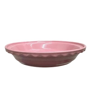May include: A round, dusty rose-colored ceramic pie dish with a glossy finish. The dish features a wide, scalloped rim and a series of three horizontal, raised rings encircling the exterior side, providing a textured detail to the simple design.