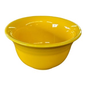 May include: A bright yellow ceramic bowl with a smooth, glossy finish and a wide, flared rim. The bowl features a deep, rounded basin and a solid, vibrant color throughout its exterior and interior surfaces, presenting a simple, functional design.
