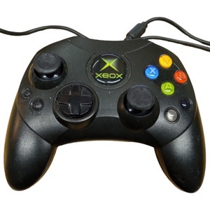 Könnte beinhalten: Ein schwarzer Xbox-Controller mit grünen und gelben Knöpfen. Der Controller hat ein grünes Xbox-Logo auf der Vorderseite.