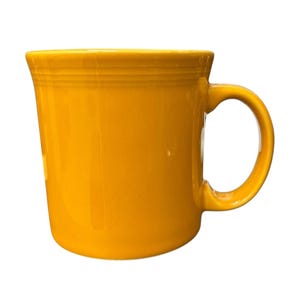 May include: A bright yellow ceramic mug with a rounded handle. The mug has a smooth, glossy finish and a slightly flared rim with horizontal ridges. The mug is designed for hot beverages.