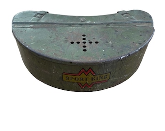 Puede incluir: Una caja de metal verde con un asa a cada lado. La caja tiene una etiqueta que dice "SPORT KING" en letras amarillas con un contorno rojo. La caja tiene una serie de pequeños agujeros en la parte superior.