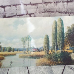 May include: A painting of a rural landscape with a river, a bridge, and trees. The sky is blue with white clouds. The river is a light blue color and the trees are green. The bridge is made of stone and is brown. The painting is in a vintage style.