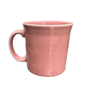 Puede incluir: Una taza de cerámica rosa con un asa curvada. La taza tiene un acabado brillante y un diseño simple y clásico. La taza es de color rosa claro liso.