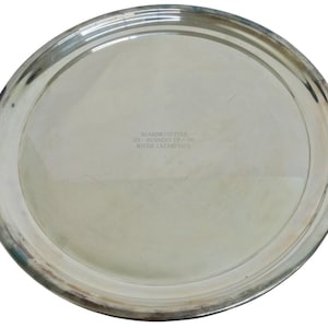 May include: A silver oval serving tray with a raised rim. The tray has etched text on the surface. The text reads "BOARDMANETTES 195- RUNNER UP - 06 RITZIE LAZAREVICH". The tray is reflective and appears to be made of metal.