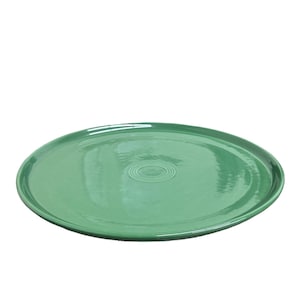 May include: A round, green serving platter with a slightly raised edge. The platter has a glossy finish and a concentric circle design in the center. The color is a vibrant, solid green, suitable for serving food.