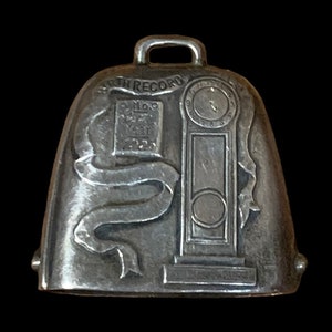 May include: Silver bell charm with a clock face, a ribbon, and the text "Birth Record 1923".