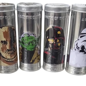 以下が含まれることがあります： スターウォーズのキャラクターグラフィックが描かれた、6つの銀色の金属製容器。ボバ・フェット、ランド・カルリシアン、ヨーダ、ダース・ベイダー、ストームトルーパー、レイア姫の画像が描かれています。容器にはテキストが書かれています。
