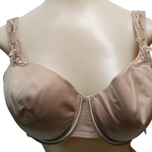 May include: A nude-colored underwire bra with delicate floral lace detailing on the straps. The bra has a smooth, seamless cup and a delicate white trim.