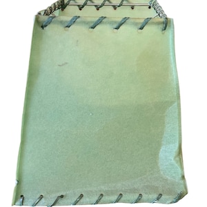 May include: A light green lampshade with a square shape and a stitched edge. The shade is made of a textured material and has a wire frame.