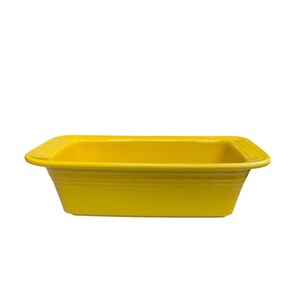 May include: A bright yellow rectangular baking dish with rounded corners. The dish has a slightly flared shape and a smooth, glossy finish. The sides feature subtle, horizontal ridges.