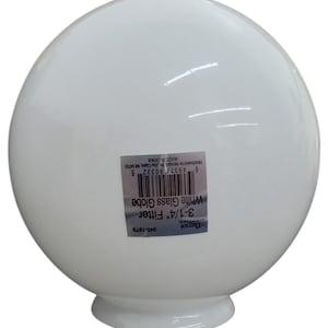 May include: A white glass globe with a 8.26 cm fitter. The globe is round and has a smooth surface. The product label includes the text "White Glass Globe" and "3-1/4" Fitter".