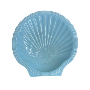 Könnte beinhalten: Eine hellblaue Keramikschale in Muschelform. Die Schale hat ein geripptes Design, das von einem zentralen kreisförmigen Muster ausgeht. Der Rand und die äußeren Kanten sind mit einem erhabenen, weißen Zierrat versehen. Die Schale ist mit einer gebogenen Kante versehen.