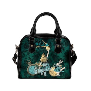 May include: A black and green handbag with a print of Alice in Wonderland characters. The print features Alice, the Cheshire Cat, the Mad Hatter, and the White Rabbit. The bag has a black strap and a top handle.