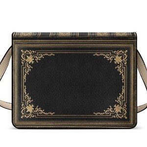 K&ouml;nnte beinhalten: Schwarze Umh&auml;ngetasche im Design eines Vintage-Buches. Die Tasche hat goldfarbene, verzierte Eckdesigns und Verzierungen auf einem schwarzen, leder&auml;hnlichen Material. Sie hat einen beigefarbenen Schulterriemen und eine rechteckige Form.