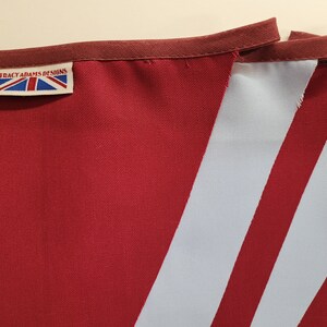 May include: A red and white striped bunting with a label that reads "Tracy Adams Designs".
