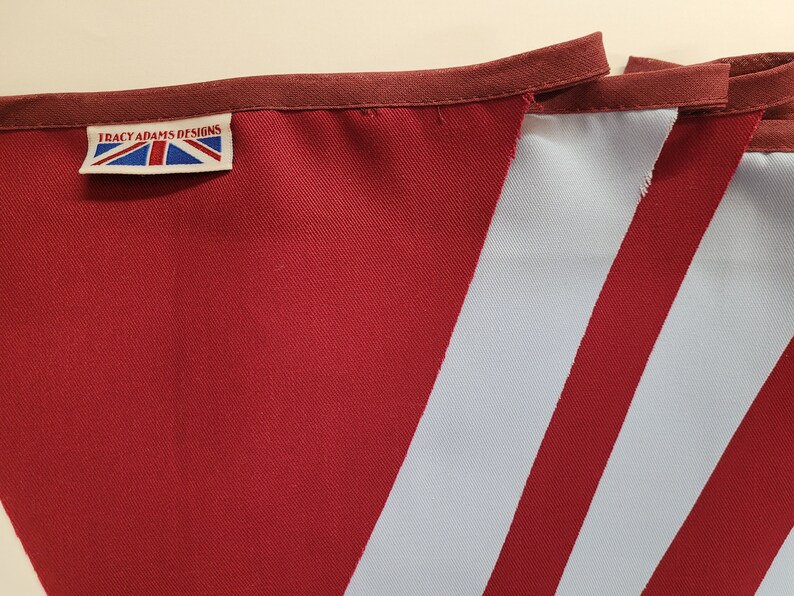 May include: A red and white striped bunting with a label that reads "Tracy Adams Designs".