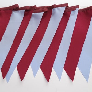 May include: A bunting banner with alternating burgundy and light blue triangular flags. The flags are sewn together to create a continuous banner.