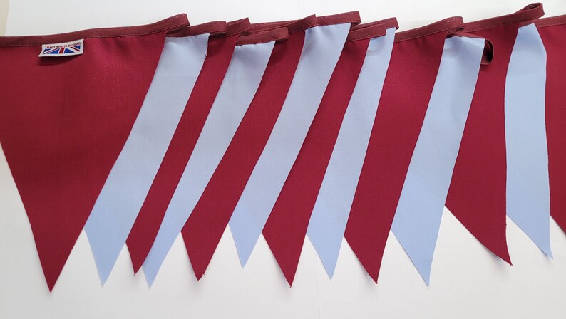 May include: A bunting banner with alternating burgundy and light blue triangular flags. The flags are sewn together to create a continuous banner.