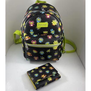 May include: A black backpack and matching wallet featuring an all-over print of colorful Pixar alien characters in various costumes. The backpack has lime green straps, silver zippers, and a rectangular patch with the text PIXAR on the front pocket.