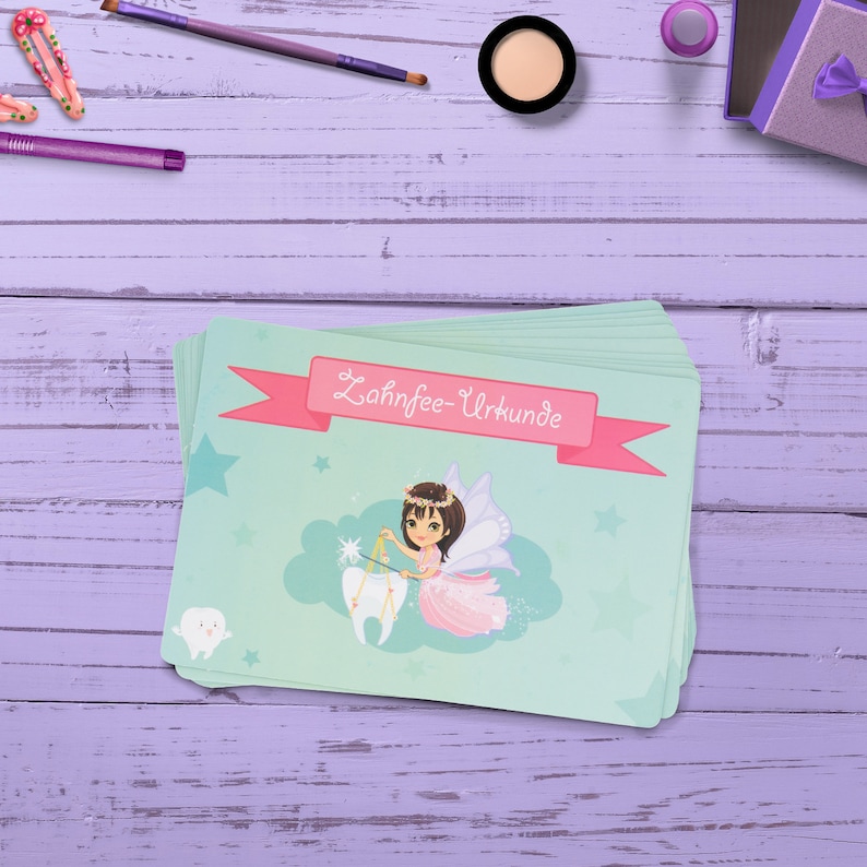 May include: A stack of green and pink cards with a tooth fairy illustration and the text "Zahnfee-Urkunde".