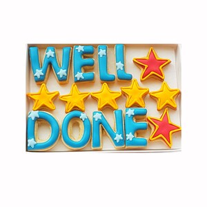 Puede incluir: Un conjunto de galletas de azúcar decoradas que deletrean "WELL DONE" con cinco galletas de estrellas amarillas y dos galletas de estrellas rojas.