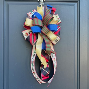 May include: A festive Christmas bow made of red, green, gold, and blue ribbon with a gold glitter finish. The bow is tied with a knot and has a long tail.
