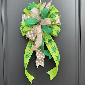 May include: A green and brown bow with a white polka dot pattern. The bow is decorated with green sea turtles.