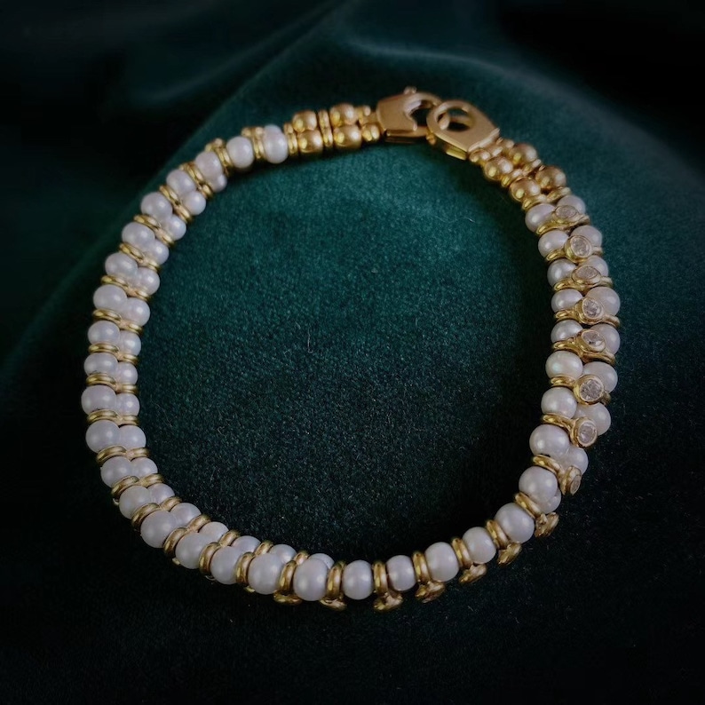 Op de afbeelding: Een gouden en witte parel armband met een sluiting. De armband heeft afwisselende gouden kralen en witte parels.