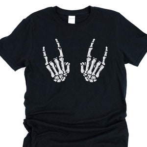 May include: Black t-shirt with a white skeleton hand graphic making a rock and roll hand gesture.