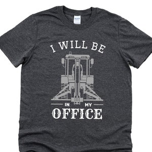 May include: A dark gray t-shirt with a white graphic of a backhoe and the text "I will be in my office".