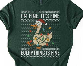 May include: Dark green t-shirt with a humorous design. The design features a cartoon duck wearing a Santa hat and wrapped in Christmas lights. The text "I'M FINE, IT'S FINE EVERYTHING IS FINE" is printed above and below the duck in white.