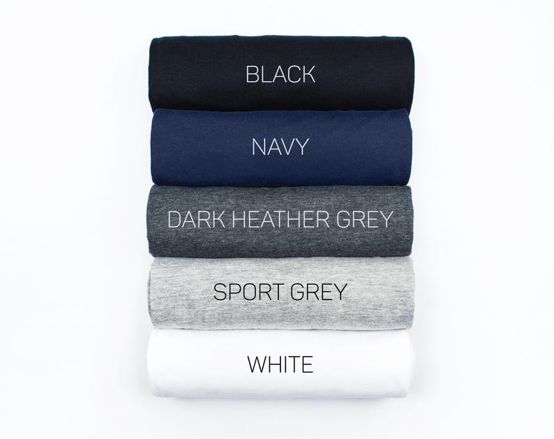 May include: Five rolled up t-shirts in different colors: black, navy, dark heather grey, sport grey, and white.