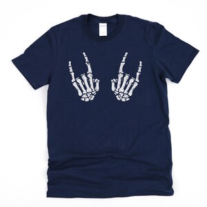 May include: A navy blue t-shirt with a white skeleton hand graphic making the rock and roll hand gesture. The graphic is on the front of the shirt.