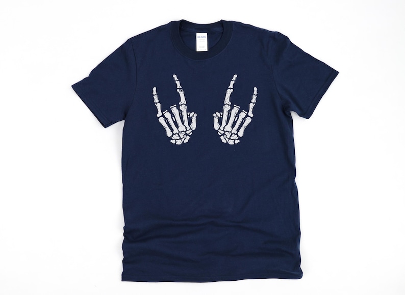 May include: A navy blue t-shirt with a white skeleton hand graphic making the rock and roll hand gesture. The graphic is on the front of the shirt.