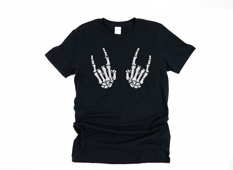 May include: Black t-shirt with a white skeleton hand graphic making a rock and roll hand gesture.