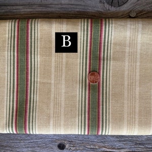May include: A roll of beige fabric with vertical stripes in burgundy and olive green. A penny is placed on the fabric. The fabric has the text "RODEO DRIVE" and the letter "B" in a black box.