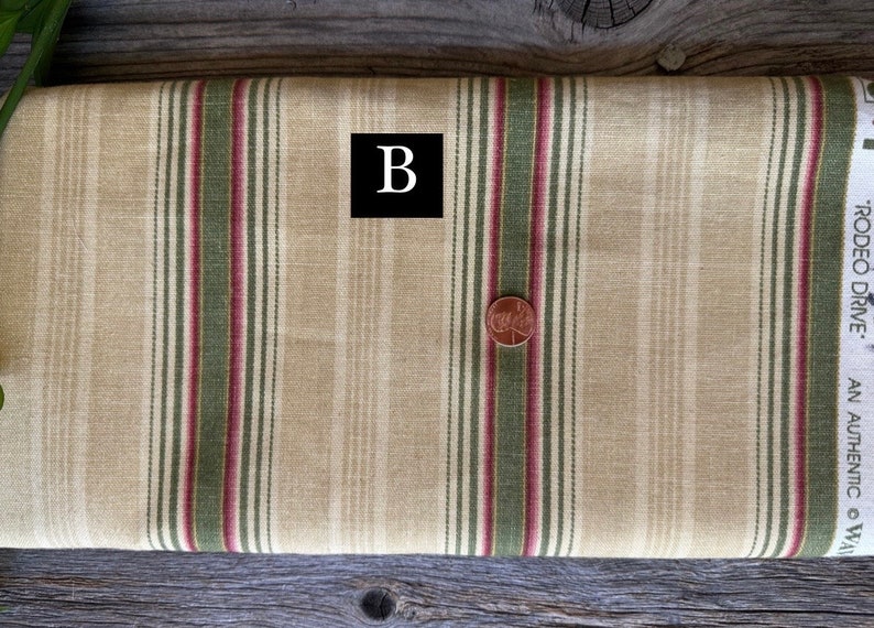 May include: A roll of beige fabric with vertical stripes in burgundy and olive green. A penny is placed on the fabric. The fabric has the text "RODEO DRIVE" and the letter "B" in a black box.