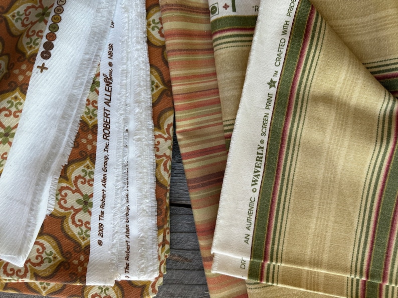 May include: Selection of fabric swatches in diverse patterns and colours. Features a white fabric strip with text from "The Robert Allen Group, Inc." and a striped fabric with "WAVERLY SCREEN PRINT" text.