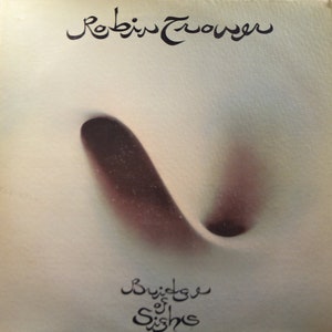 May include: A vintage record album cover featuring a black and white illustration of a swirling vortex. The album is titled "Buried  of Sishc" and the artist is "Robin Trower".