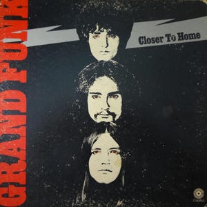 May include: Vintage vinyl record album cover for Grand Funk, featuring three band member portraits. The album title "Closer To Home" is displayed in white text on a gray banner. The band's name is in large red letters.